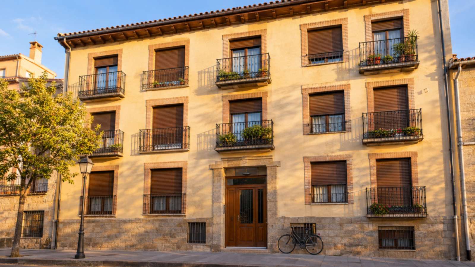 Fachada de edificio residencial castellano con balcones y una bicicleta en el portal
