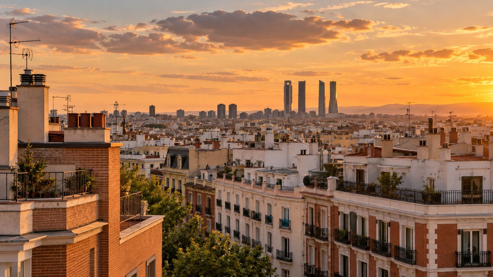 Tejados y edificios residenciales de Madrid al atardecer con las Cuatro Torres al fondo